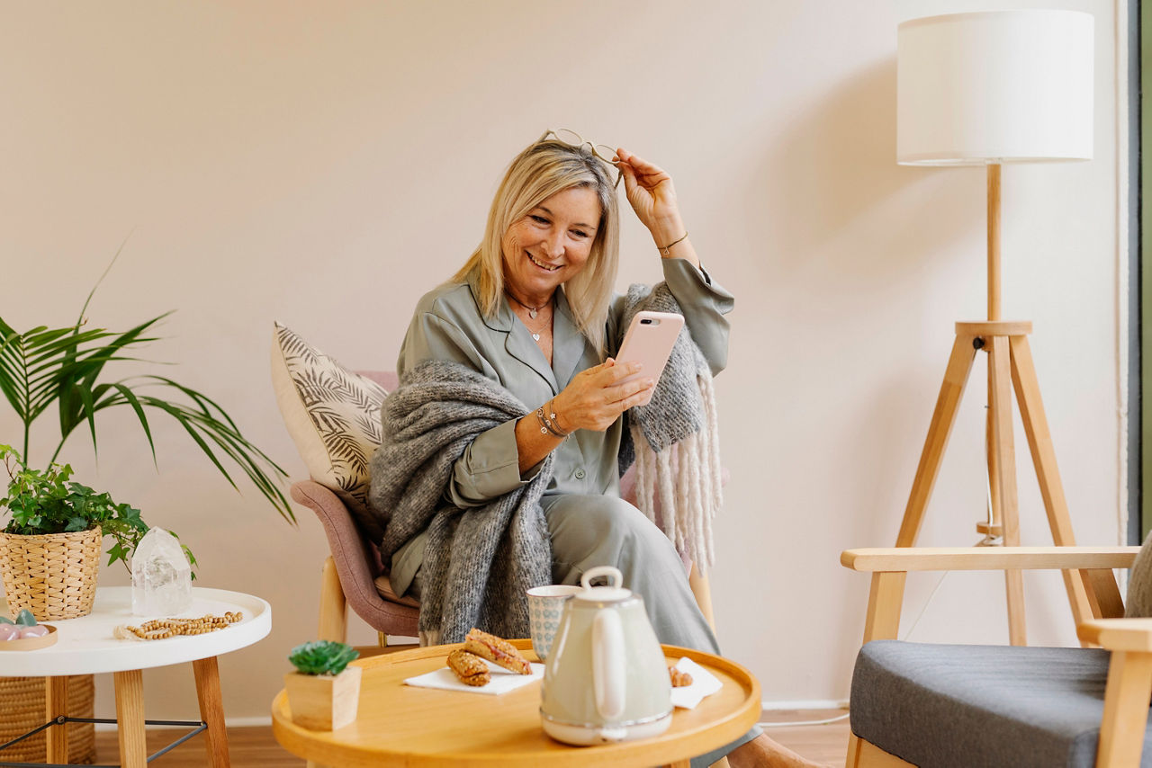 Mature woman using her mobile phone while enjoying free time relaxing at home. Technology concept.