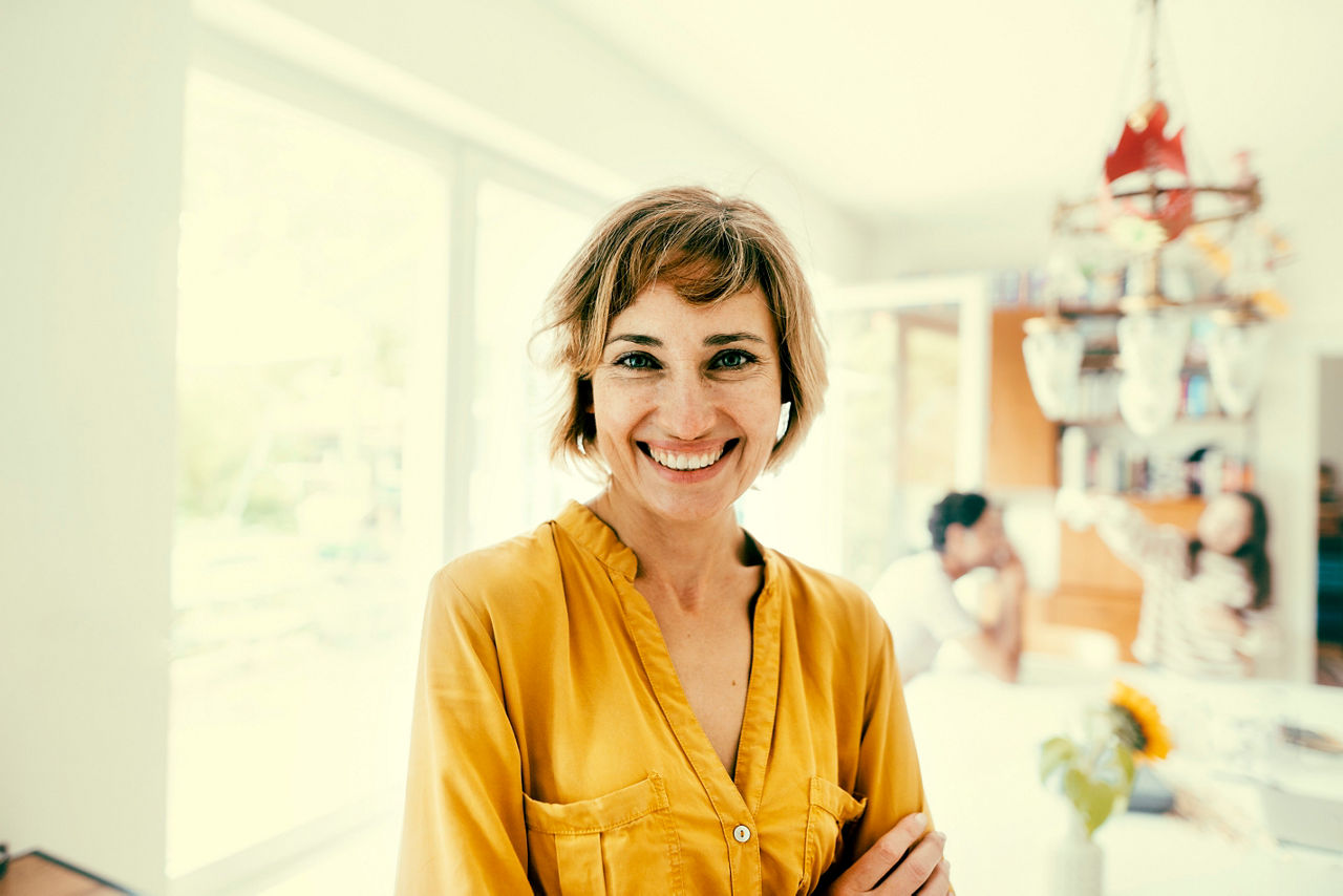 Happy woman with blond hair standing at home