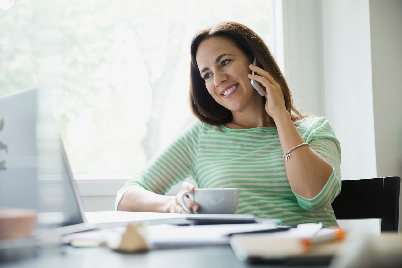 Smiling businesswoman using smart phone in home office