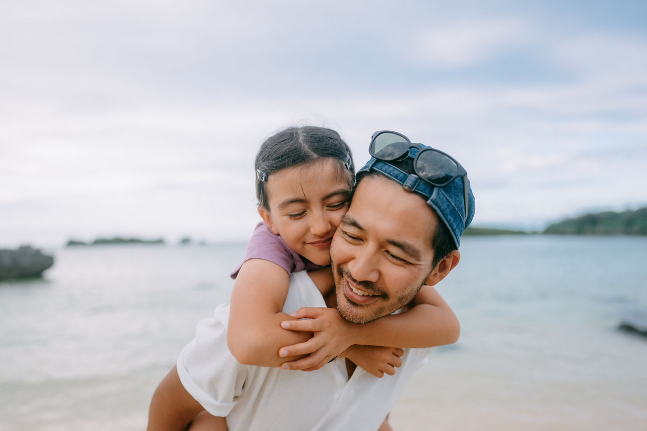 Close up of Japanese father and his young daughter having a good time on beach at dusk, Japan