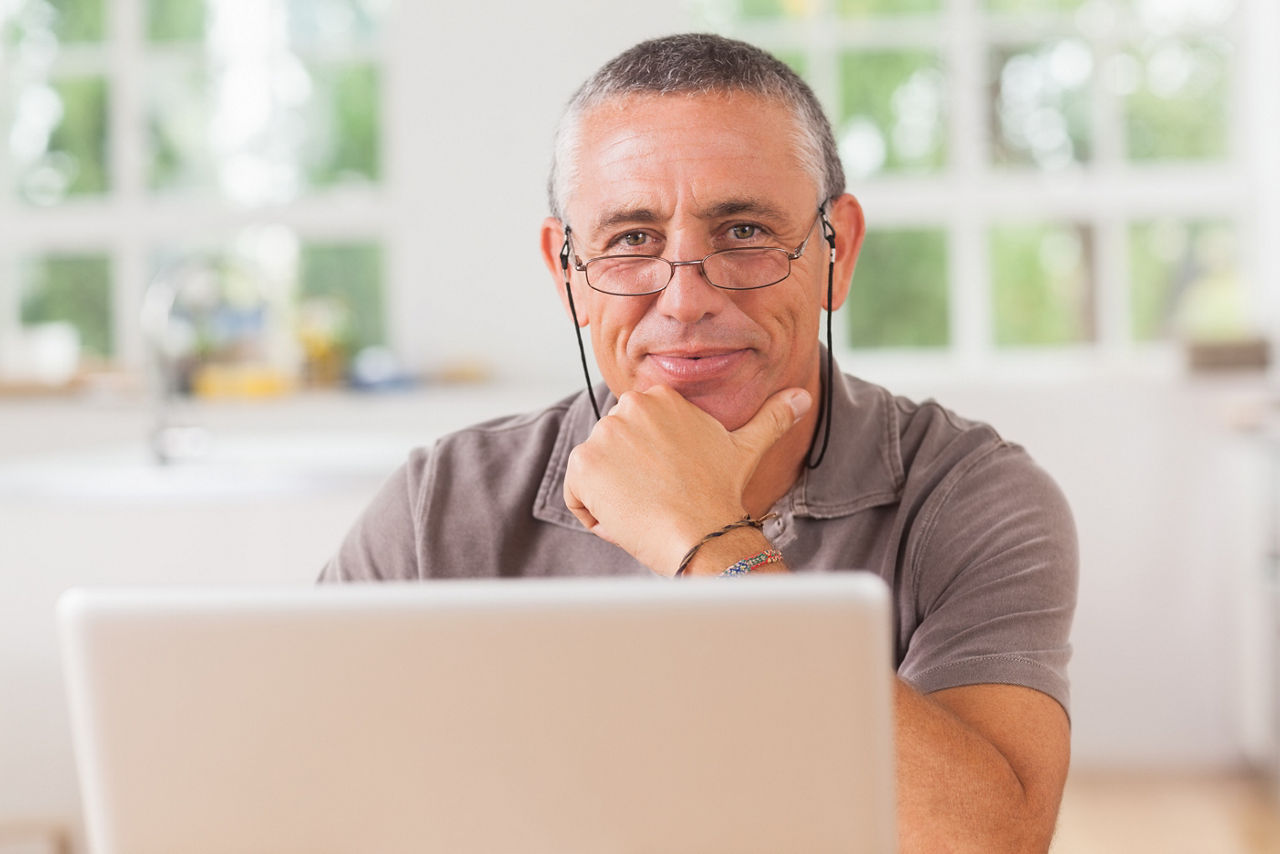 Happy man with laptop in kitchen