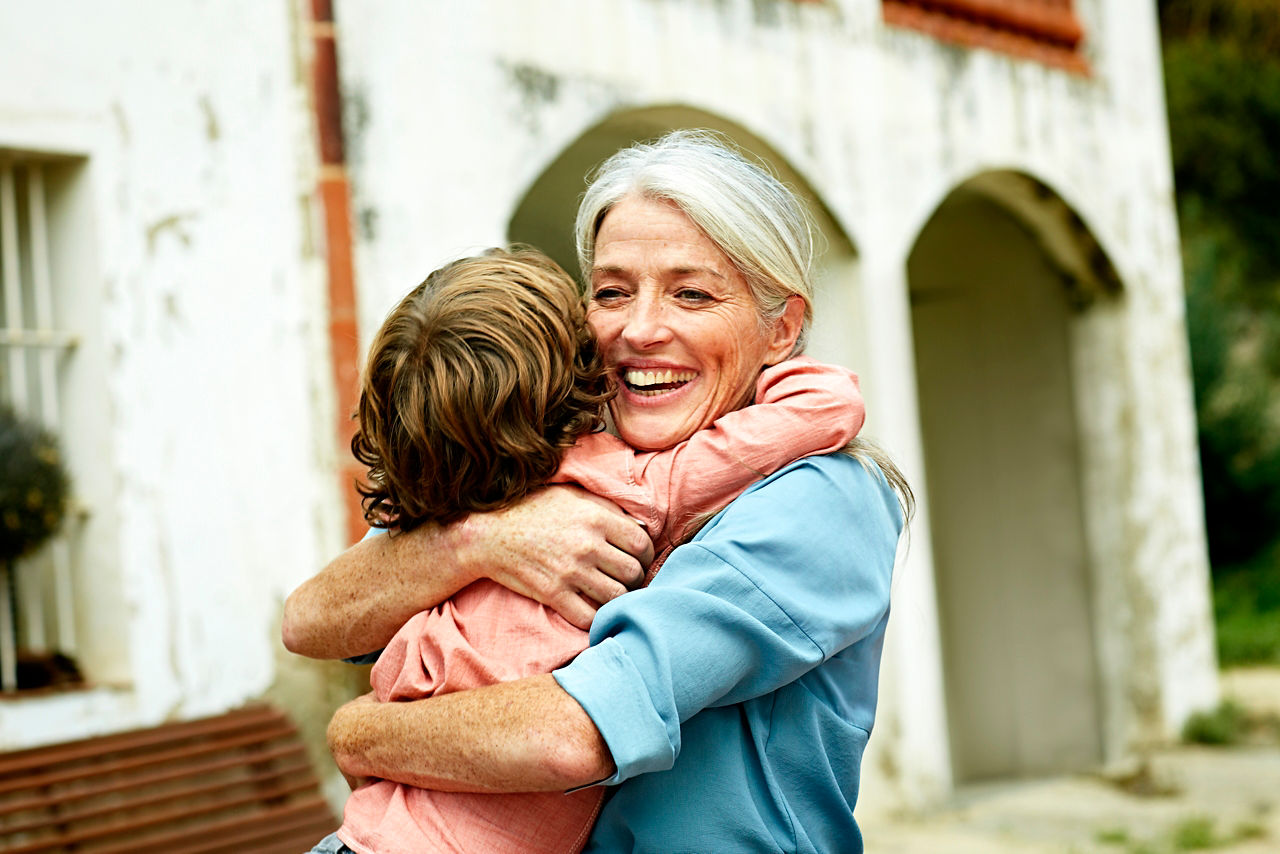 Happy grandmother looking away while embracing grandson in yard