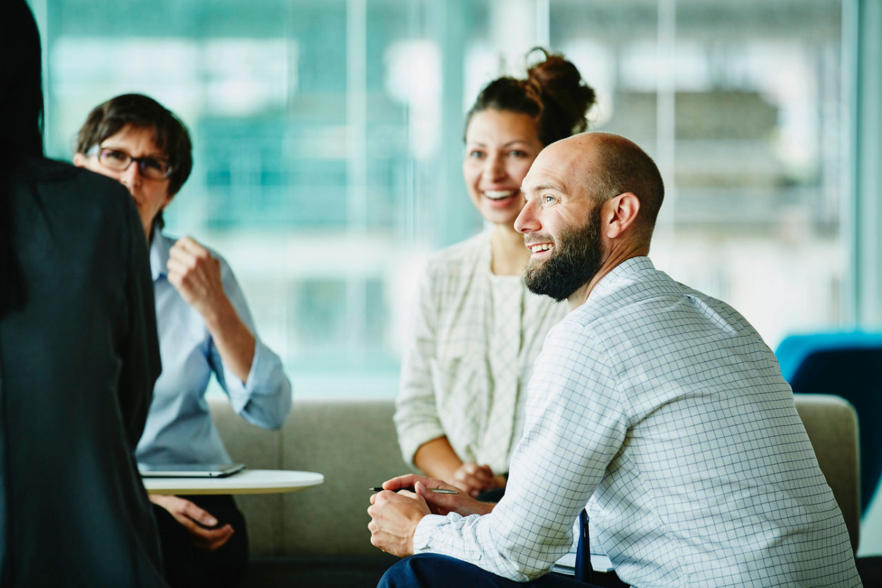 Smiling businessman in discussion with colleagues during informal project meeting in office