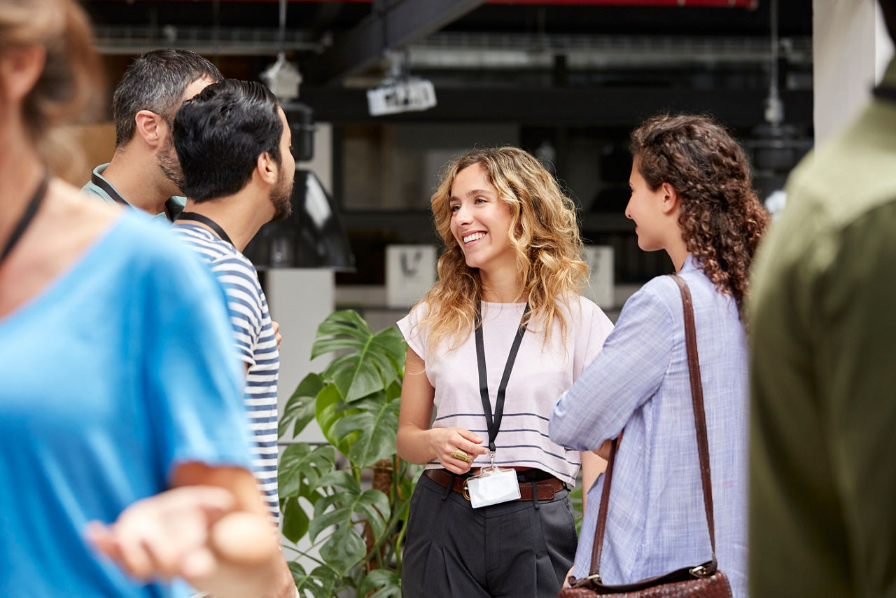 Smiling business team standing at convention center. Male and female professionals are discussing during meeting. They are wearing smart casuals.