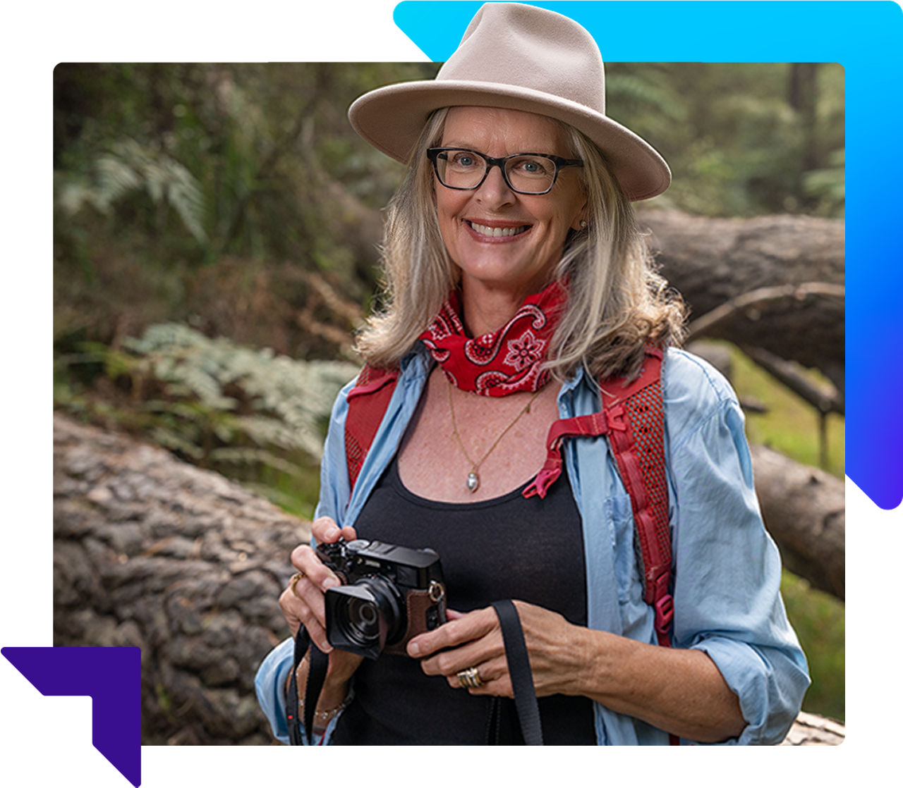 Smiling woman wearing a felt hat and holding a camera