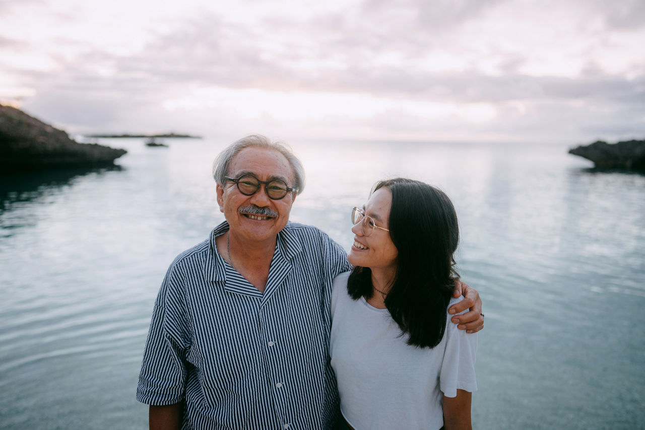 Cheerful grandfather and granddaughter having a good time on beach at dusk, Miyako Island, Okinawa, Japan
