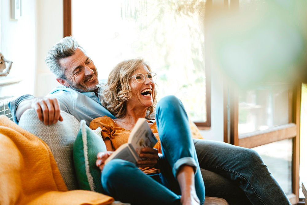 Cheerful mature couple sitting on sofa at home