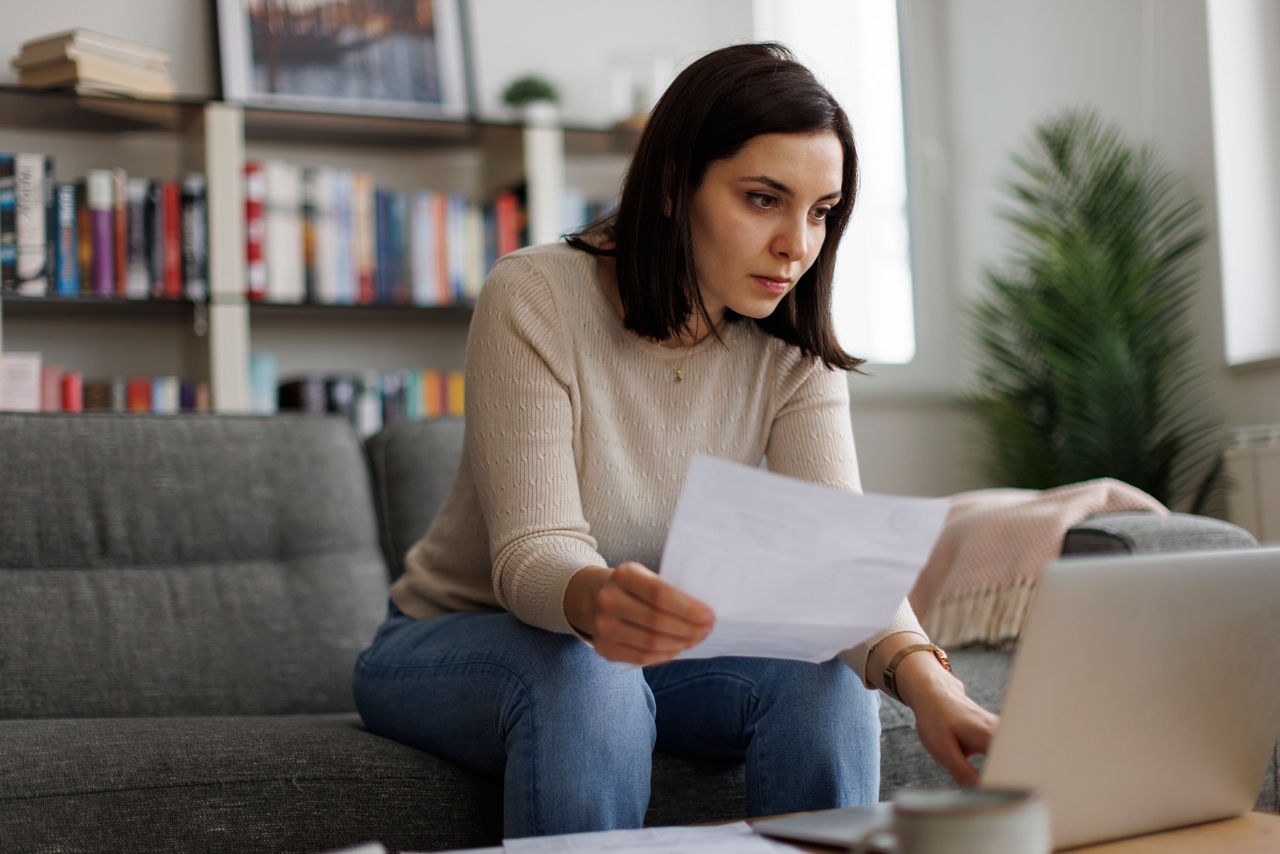 Woman planning her finances, reviews paperwork for insurance, loans, and online investments