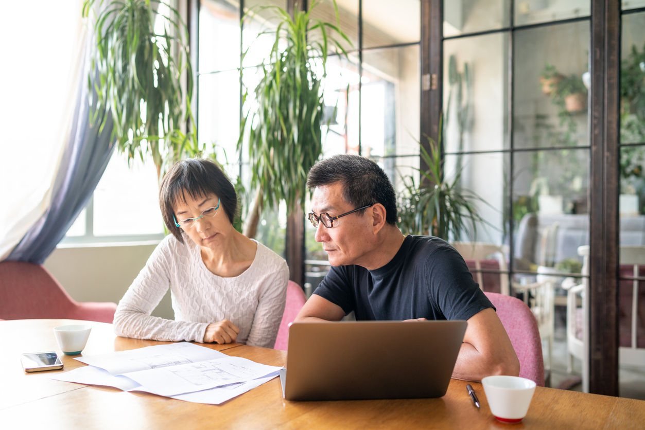 Asian couple looking at blueprints of their new house.