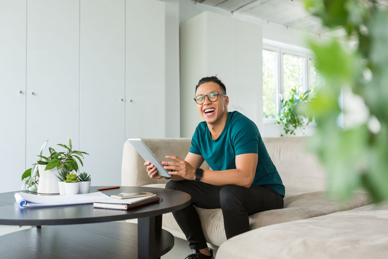 Asian handsome young man sitting in an office and using digital tablet. Hipster working in creative workplace.